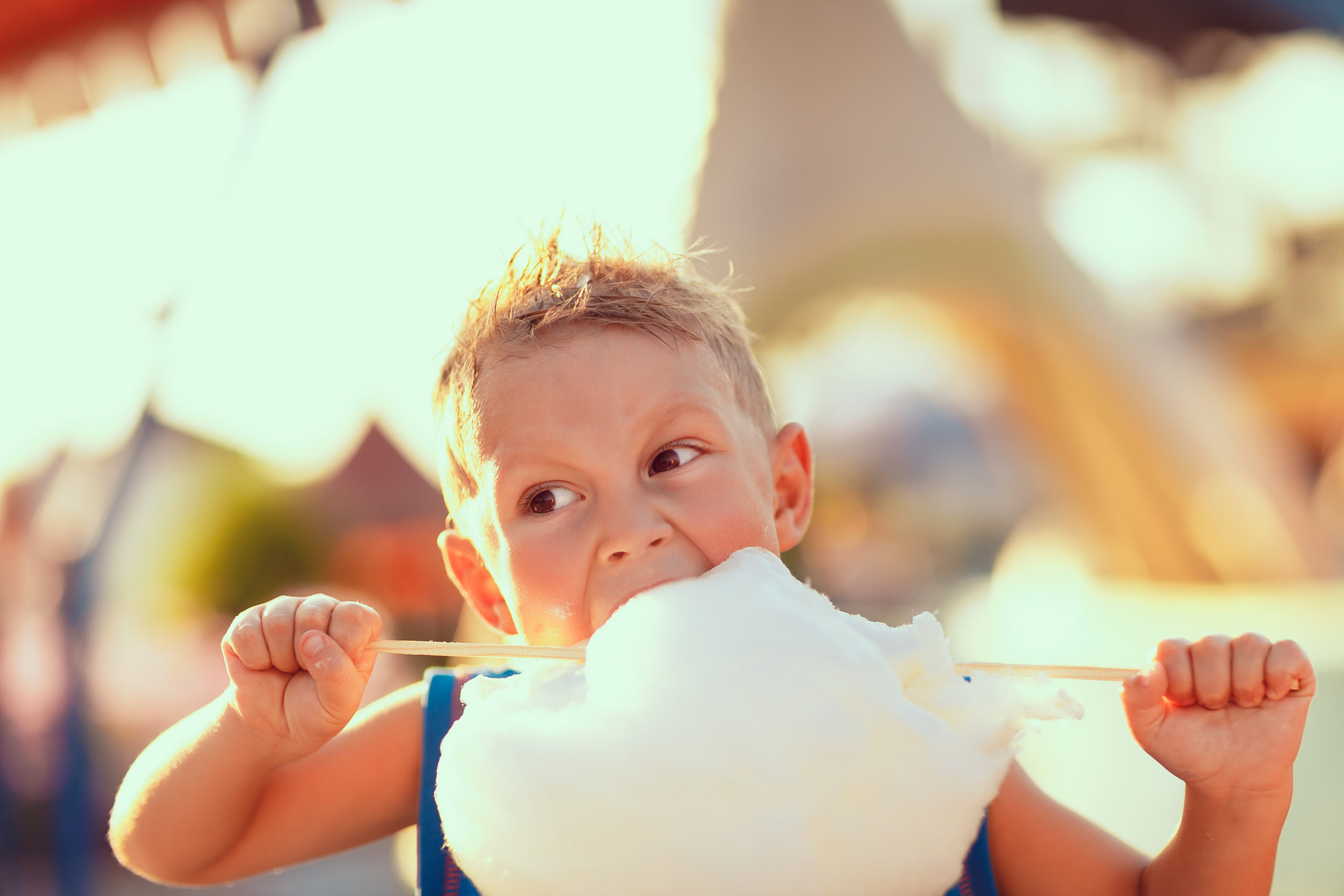 Young,Boy,Standing,And,Biting,Candy,Cotton,On,The,Street